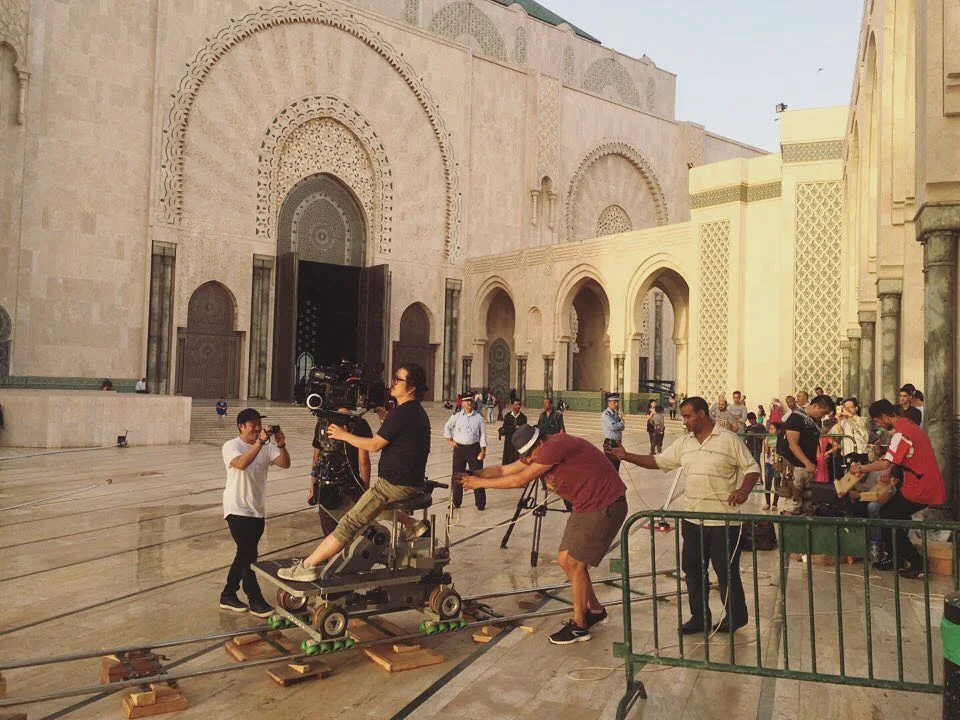 Crew pushing a camera dolly across a plaza in front of a mosque during the Samsung QLED production